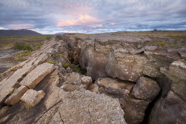 Red column in the plain with dramatic clouds in the evening sky in the fault zone