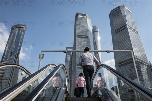 Passers-by on an escalator on a bridge in the financial district of Pudong