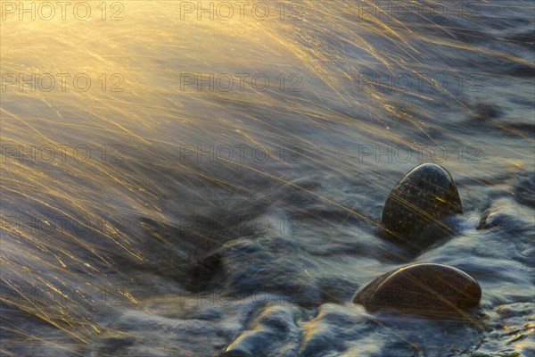 Waves and spray on the beach at sunrise