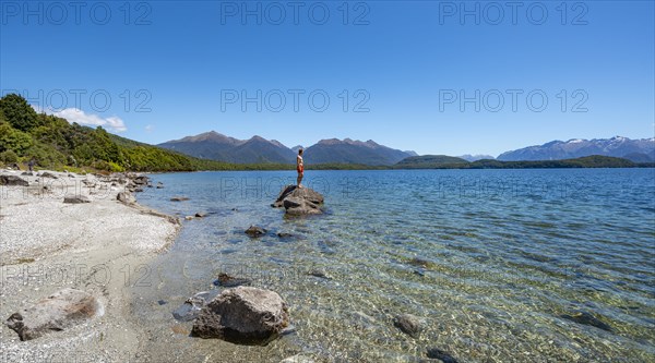 Young man standing on stone in water