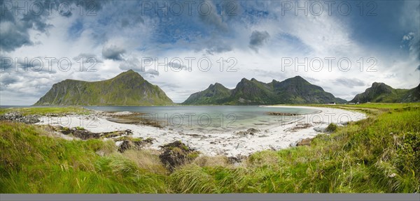 White sandy beach in front of green mountain peaks near Flakstad