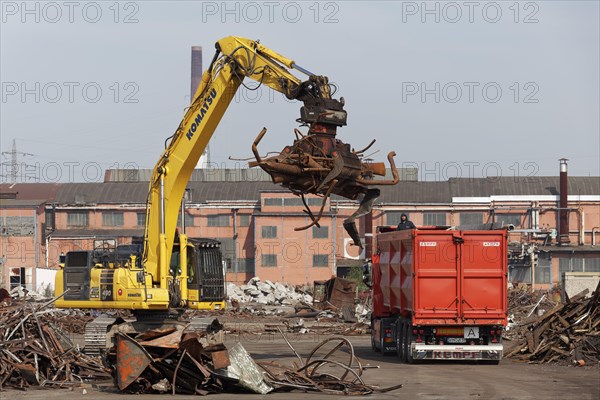 Excavator loads metal scrap onto truck