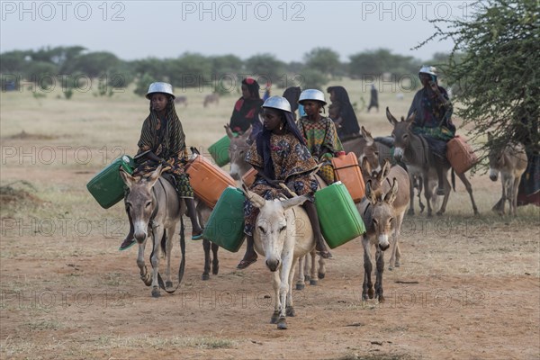 Young girls on donkeys on their way to a waterhole