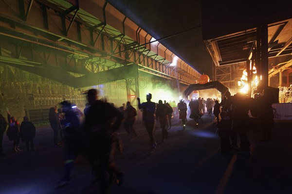 Runners in front of an illuminated industrial scenery