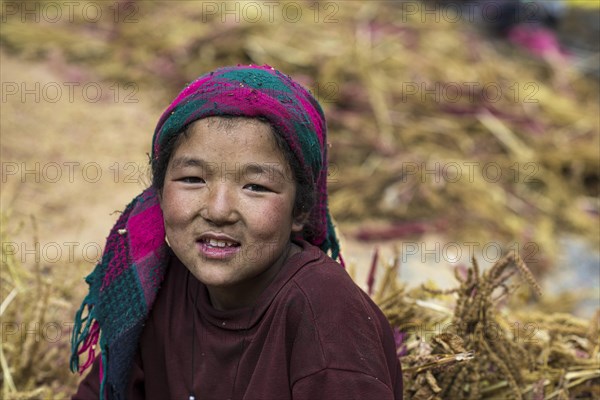 A little girl sitting in a pile of pearl millet