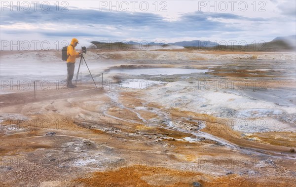 Man in yellow jacket with photo tripod