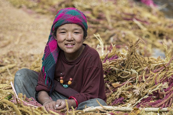 A little girl sitting in a pile of pearl millet