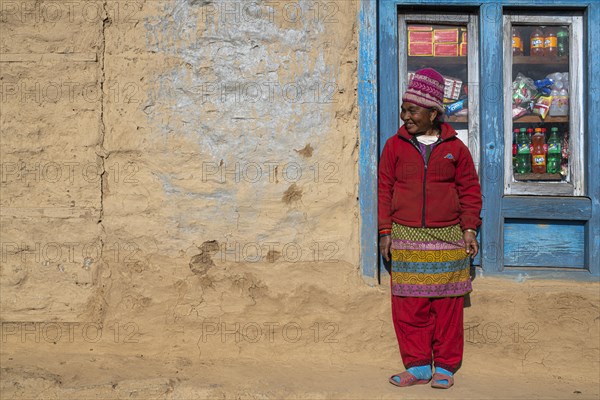 A local woman is standing in front of the window of her shop