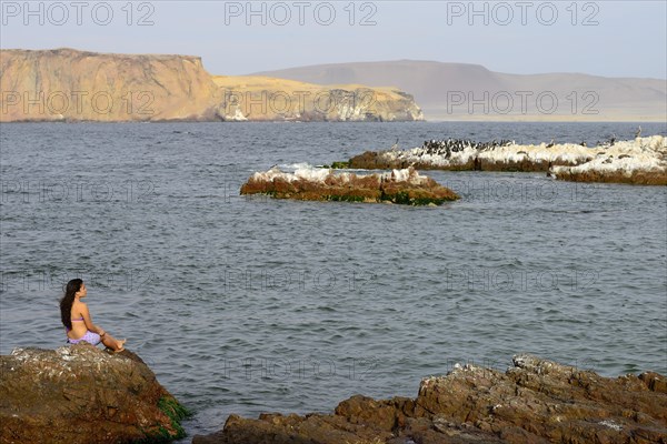 Woman sitting on a rock in Paracas National Reserve