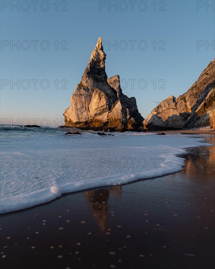 Marked rocks at Praia da Ursa beach with reflection and foamy sea water