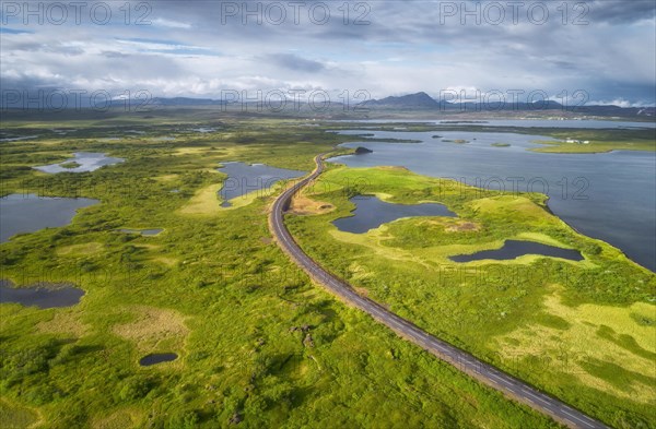 Aerial view of road through green landscape with volcanic crater