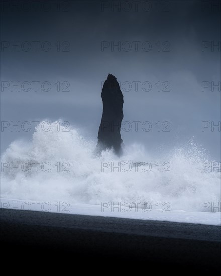 Sharp rock with strongly breaking waves on a volcanic beach