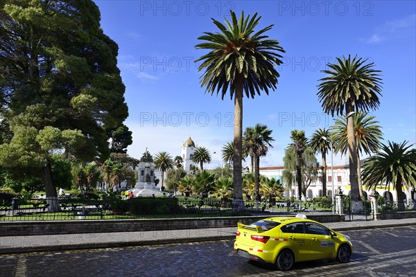 Yellow taxi in front of the Parque Vicente Leon with its monument