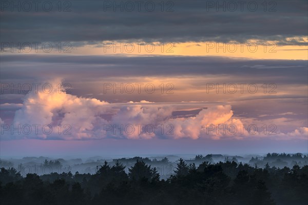 Clouds illuminated by the rising sun and morning mood with sea fog over Henne Strand