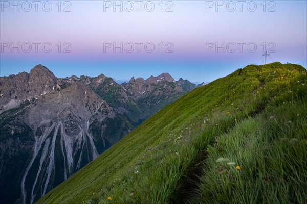 Small mountain trail with flower meadow and summit of the Uentschenspitze at sunrise