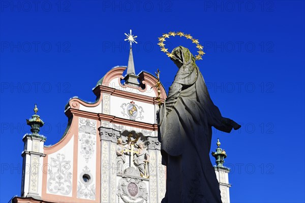 Statue of the Virgin Mary with a halo in front of a decorative facade