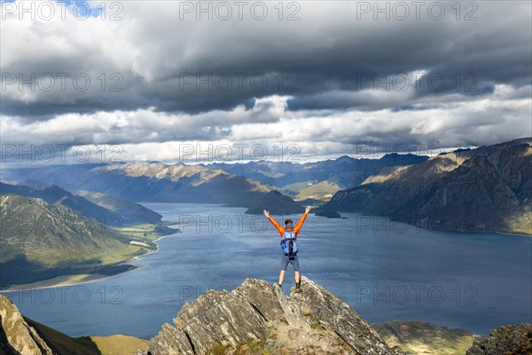 Hiker stands on a rock and stretches his arms in the air