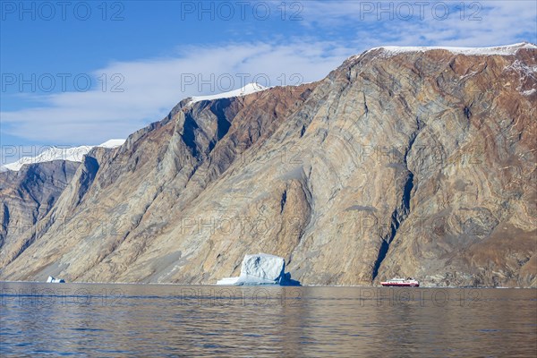 Iceberg and cruise ship in fjord