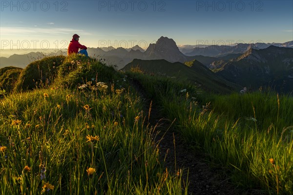 Small mountain trail with mountaineers and summits of the Allgaeuer Alps at sunrise