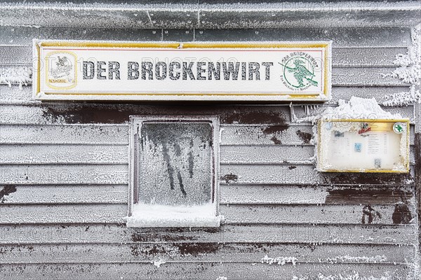 Shield The Brockenwirt on snow-covered wooden facade with window