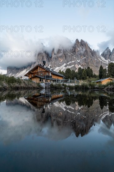 Reflection from the Furchetta mountain and the Geisler Alm hut in a pond near the Geisler Alm