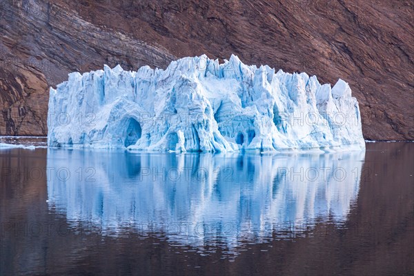 Iceberg in front of rock in fjord