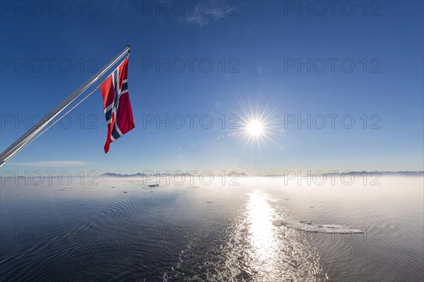 Norwegian flag waving over fjord in Greenland