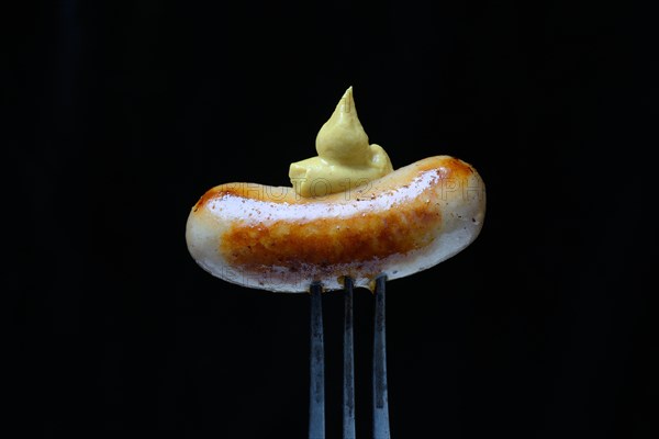 Chipolata sausages with mustard on fork