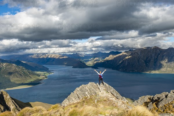 Hiker stands on a rock and stretches her arms in the air