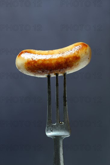 Chipolata sausages on fork