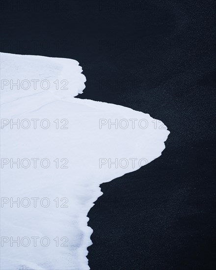 White wave on black lava sand