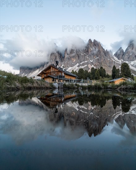 Reflection from the Furchetta mountain and the Geisler Alm hut in a pond near the Geisler Alm