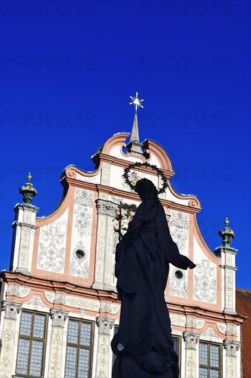 Statue of the Virgin Mary with a halo in front of a decorative facade