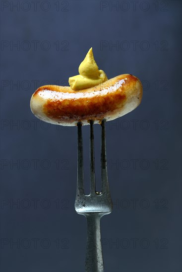 Chipolata sausages with mustard on fork