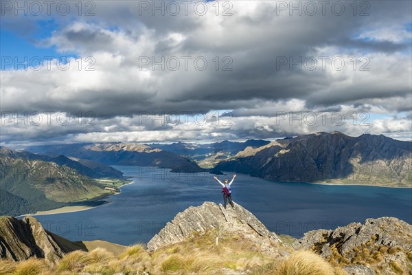 Hiker stands on a rock and stretches her arms in the air