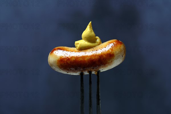 Chipolata sausages with mustard on fork