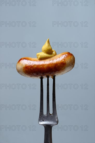 Chipolata sausages with mustard on fork