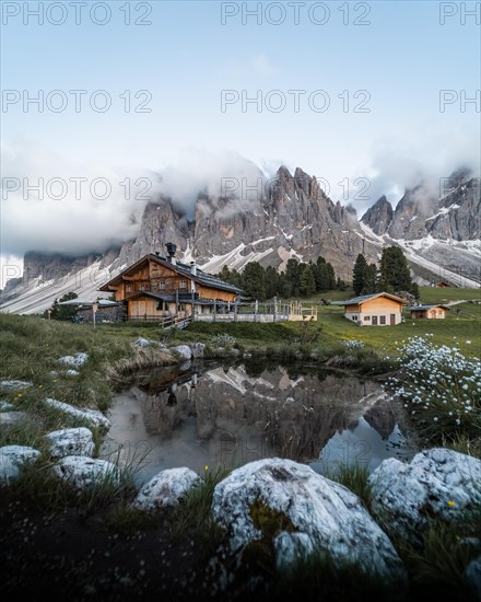 Reflection from the Furchetta mountain and the Geisler Alm hut in a pond near the Geisler Alm