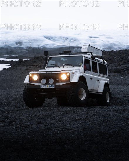 White Land Rover in front of a glacier
