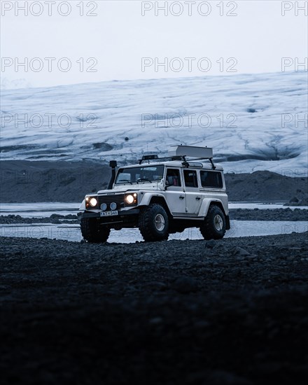 White Land Rover Jeep in front of a glacier