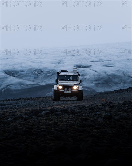 White Land Rover Jeep in front of a glacier