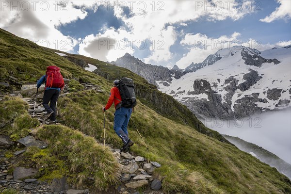 Hikers in front of snow-covered mountain peaks