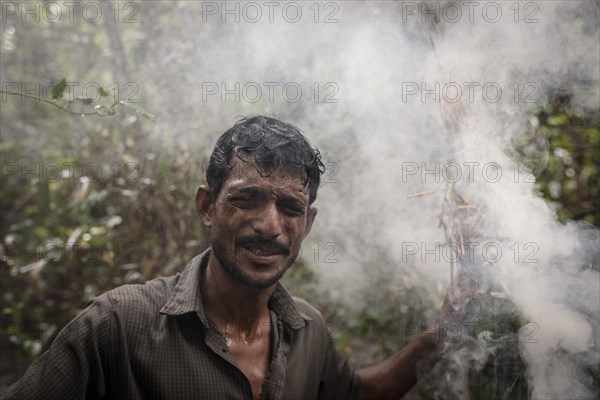 Honey collectors shortly after lighting damp perennials and leaves with fire accelerator