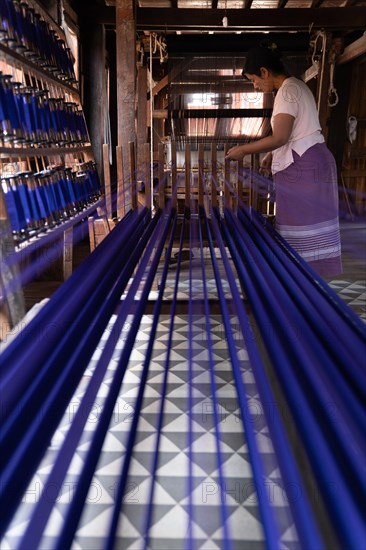 Woman pulling up colourful threads on loom