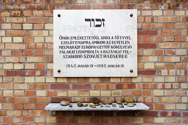 Memorial plaque commemorating the liberation of the Jewish ghetto on a wall of red bricks