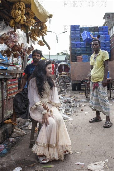 Bride sitting in front of a market stall