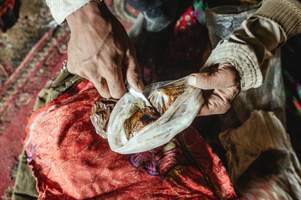 Man scrapes opium with a knife from a plastic bag