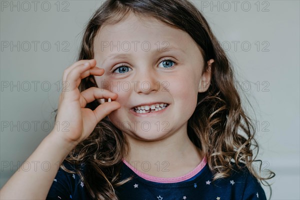 Girl with gap and fallen tooth in her hand