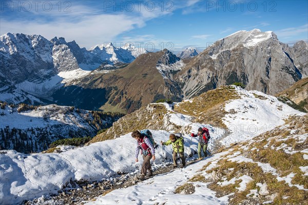 Three hikers on hiking trail with snow in autumn