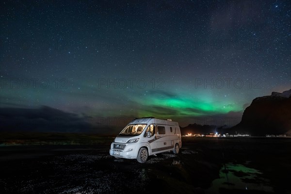 Campervan stands at Uttakleiv beach with northern lights